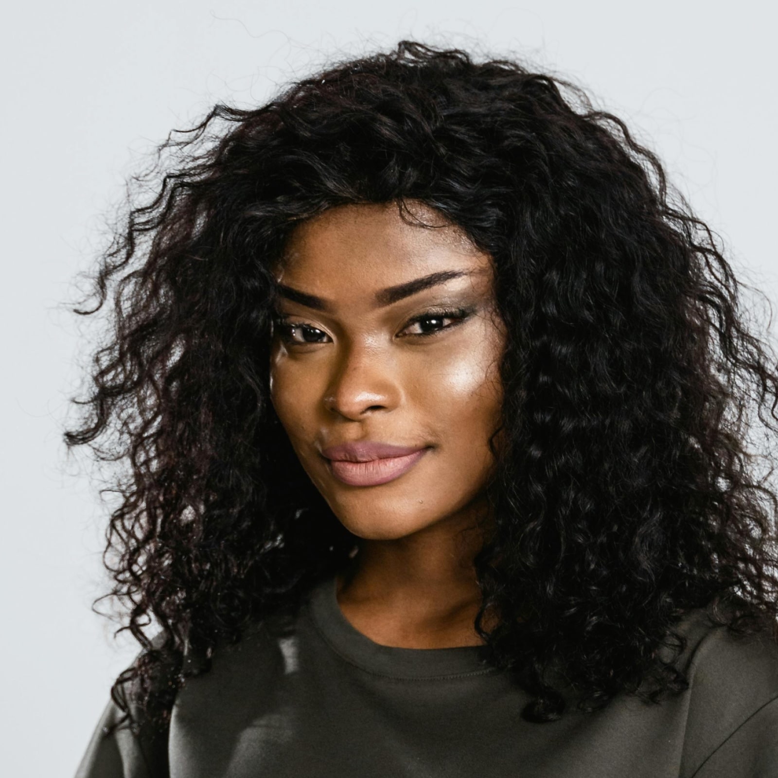 Woman with curly hair in dark shirt looking confidently to the side